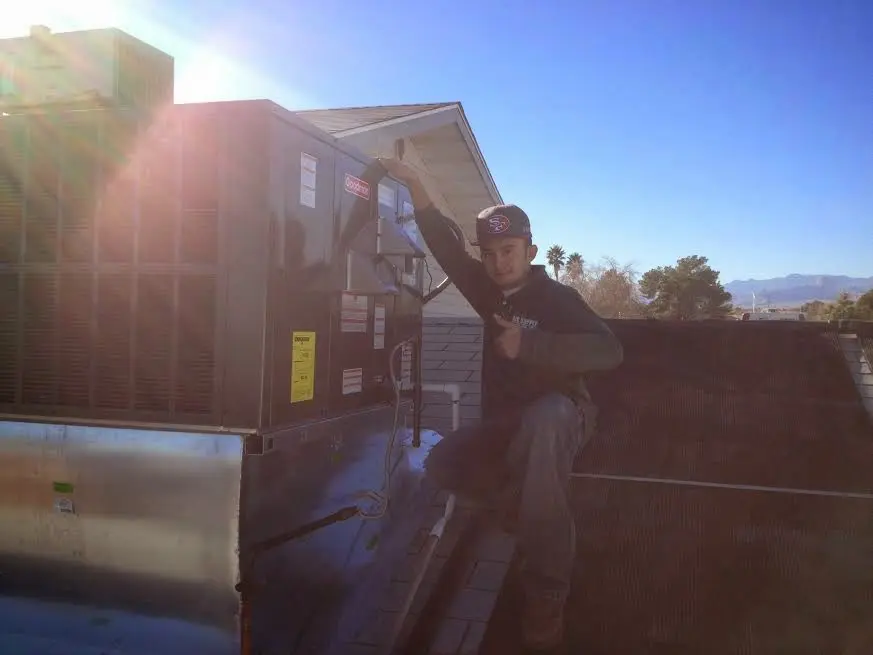 HVAC technician performing AC Tune-Up on a rooftop unit in Stoughton